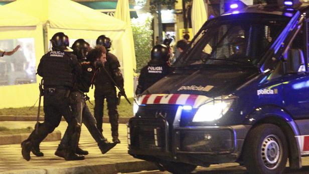 Polizisten führen einen Mann in der Nähe eines Polizeiwagens ab.