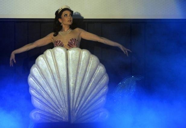 Eine Frau in einem Meerjungfrauenkostüm mit Muscheln und Krone posiert.