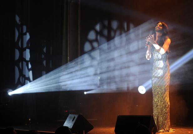 Conchita Wurst steht in einem glitzernden Kleid auf der Bühne und singt.