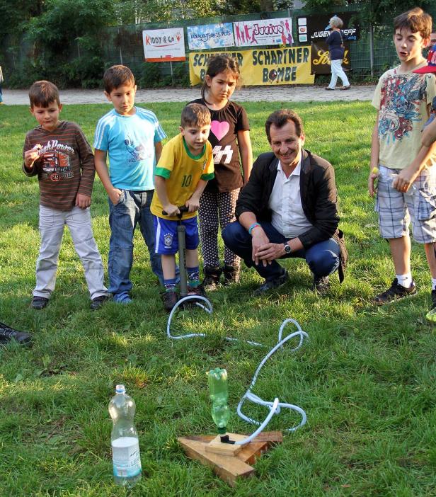 Eine Gruppe Kinder beobachtet, wie ein Junge eine Wasserrakete mit einer Luftpumpe startet.