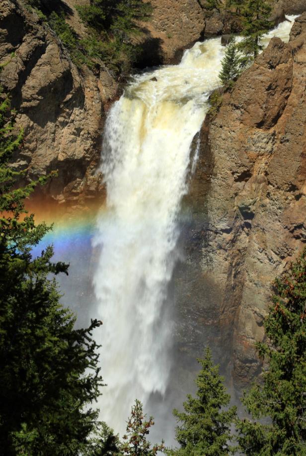 Ein Wasserfall stürzt zwischen Felsen in die Tiefe, ein Regenbogen ist sichtbar.