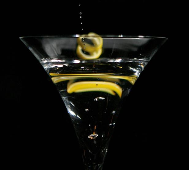 Ein Martini mit Zitronenzeste vor schwarzem Hintergrund.