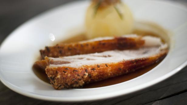 Ein Teller mit gebratenem Schweinefleisch und einer Kartoffelknödel in Soße.