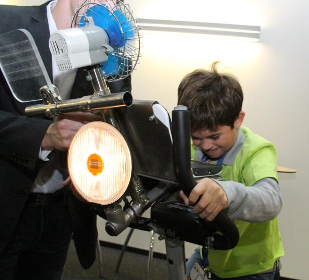Ein Junge benutzt ein ungewöhnliches Trainingsgerät mit Ventilator und Lampe.