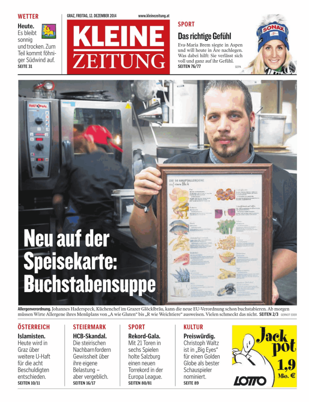 Ein Koch präsentiert eine Tafel mit den 14 Hauptallergenen in einem Restaurant.