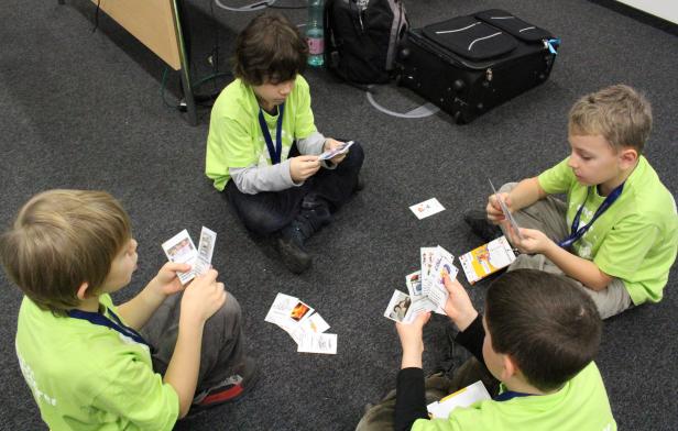 Vier Jungen sitzen auf dem Boden und spielen mit Karten zum Thema Energie.
