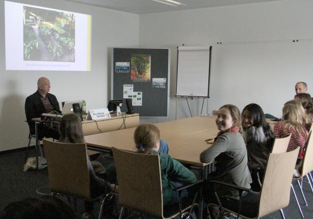 Ein Mann hält einen Vortrag vor einer Gruppe von Zuhörern in einem Konferenzraum.