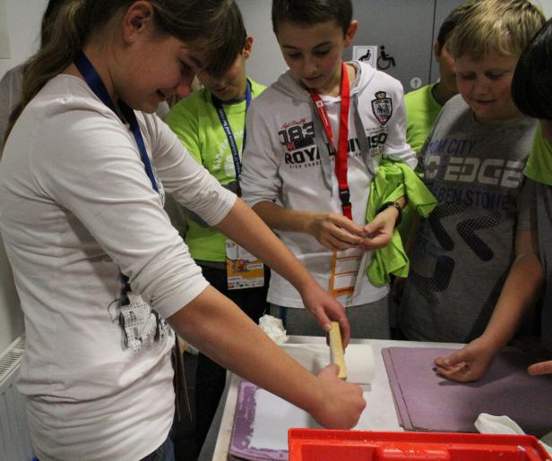 Eine Gruppe von Kindern arbeitet an einem Tisch mit Papier und Farbe.