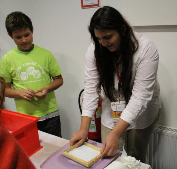 Eine Frau und ein Junge stellen Papier in einer Werkstatt her.