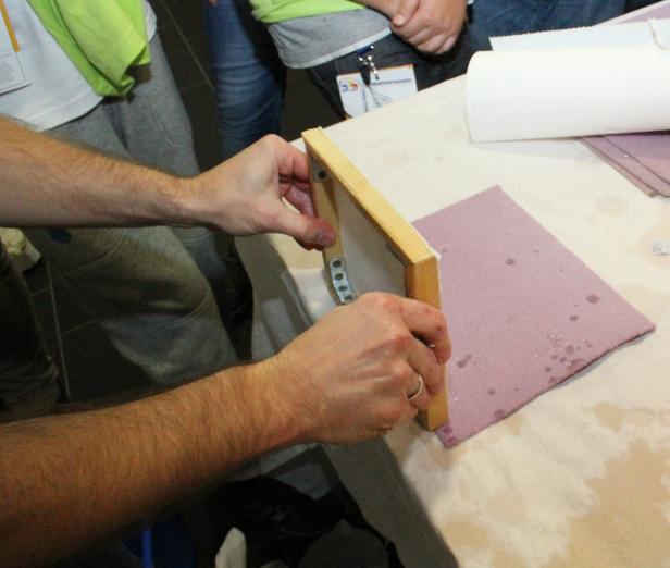 Eine Person fertigt Papier mit einem Schöpfrahmen an.