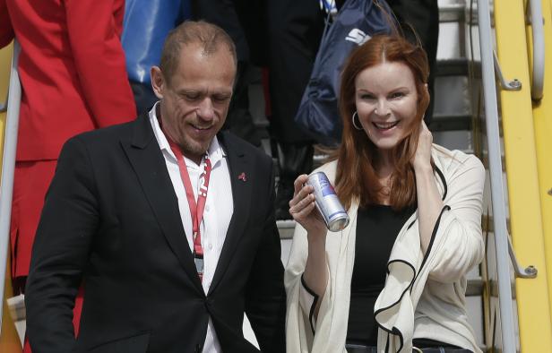 Ein Mann im Anzug und Marcia Cross mit einer Dose Red Bull lächeln.