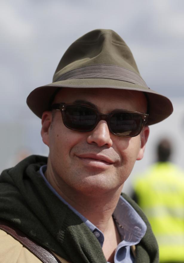 Ein Mann mit Hut und Sonnenbrille lächelt in die Kamera.