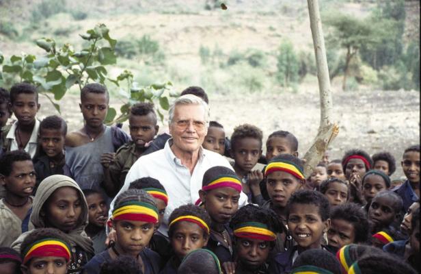 Ein Mann umringt von einer Gruppe äthiopischer Kinder, viele mit Stirnbändern in den Farben der Landesflagge.