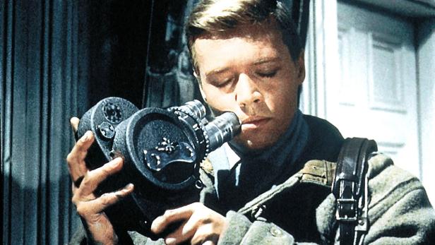 Ein junger Mann blickt durch ein großes Fernglas.