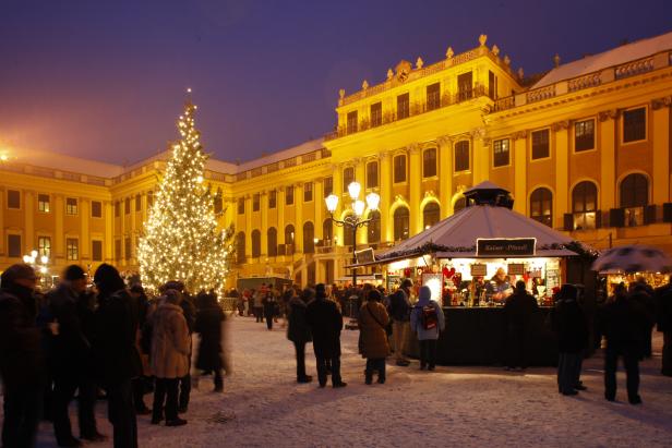 Ein Weihnachtsmarkt mit geschmücktem Baum vor dem Schloss Schönbrunn in Wien.