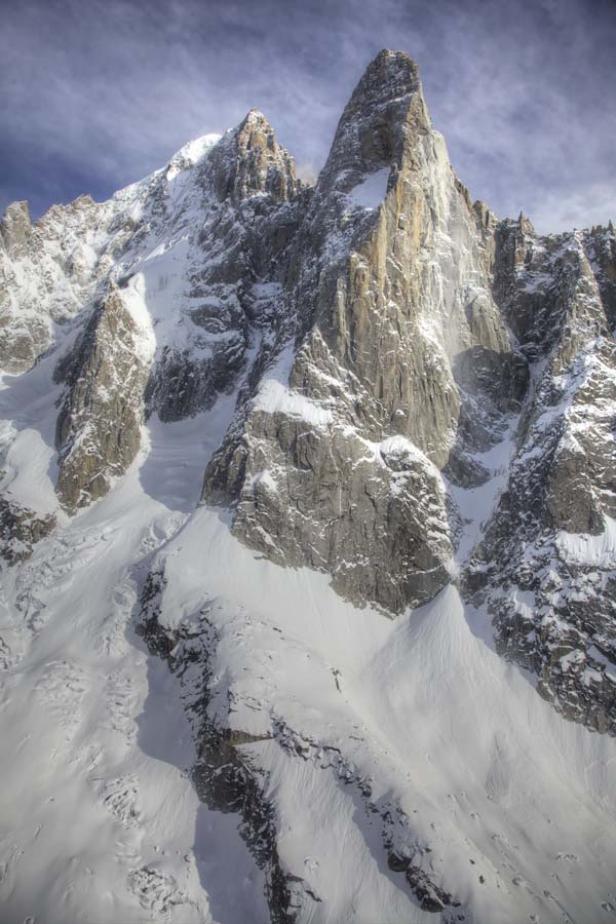 Schnee bedeckt die steilen Felswände eines hohen Berges.