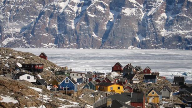 Blick auf eine Siedlung mit bunten Häusern vor einer verschneiten Bergkulisse.