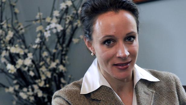 Eine Frau mit Blazer und weißem Kragen lächelt in die Kamera.