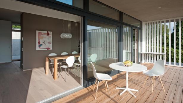 _weitblick-002_kba_junger_beer_gratis_essen terrasse_dsc9048.jpg.jpg Blick durch eine Glasschiebetür auf einen Essbereich und eine Terrasse mit Tisch und Stühlen.