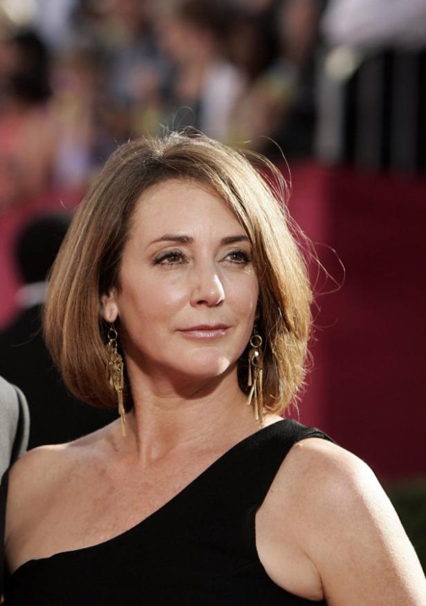 Eine Frau mit braunen Haaren und einem schwarzen Kleid posiert für ein Foto.