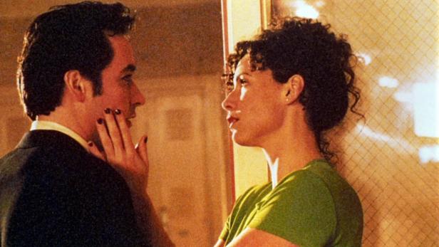 Ein Mann berührt das Gesicht einer Frau, beide schauen sich an.