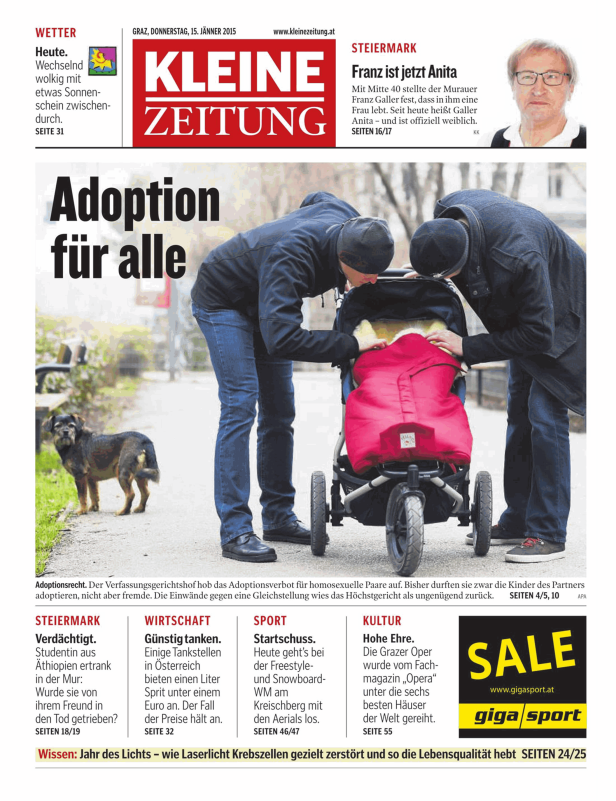 Zwei Personen beugen sich über einen Kinderwagen; im Hintergrund ein Hund.