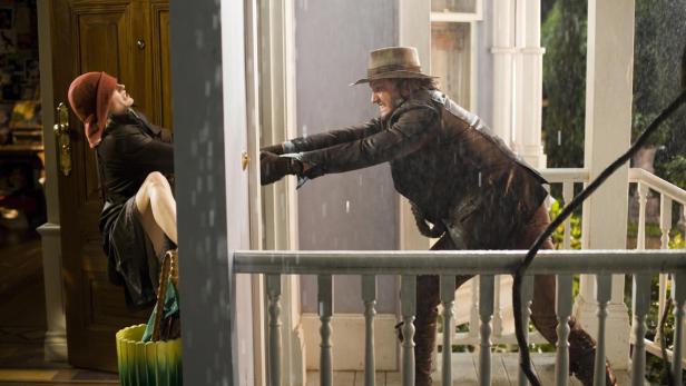 Ein Mann versucht, während eines Regensturms eine Frau aus einem Haus zu ziehen.