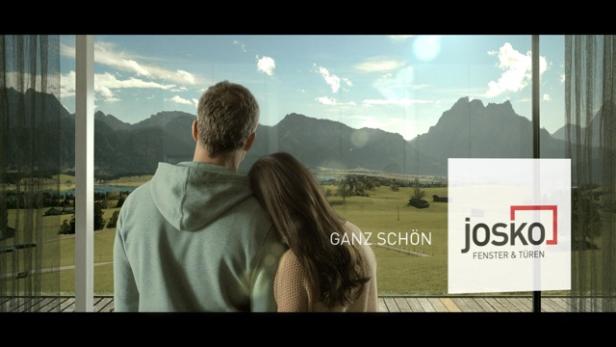 Ein Paar genießt die Aussicht auf die Berge durch ein großes Fenster der Marke Josko.