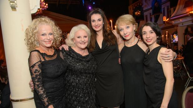 Fünf Frauen posieren in schwarzen Kleidern für ein Foto bei einer Veranstaltung.