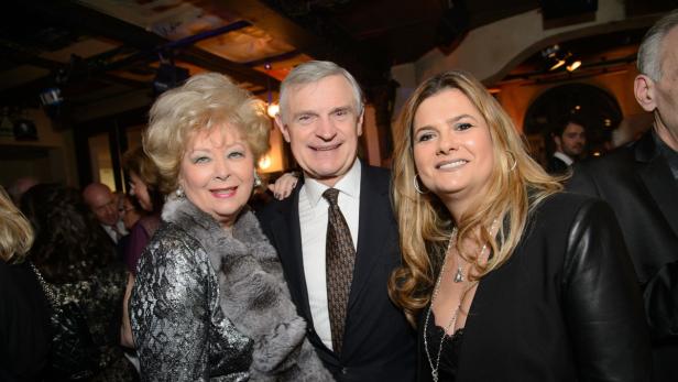 Drei Personen posieren lächelnd für ein Foto bei einer Veranstaltung.