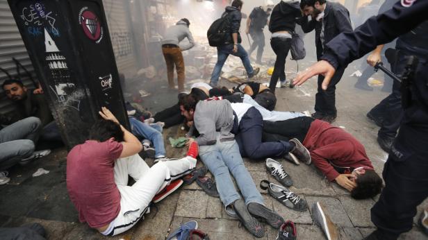 Polizisten stehen über am Boden liegenden Demonstranten.