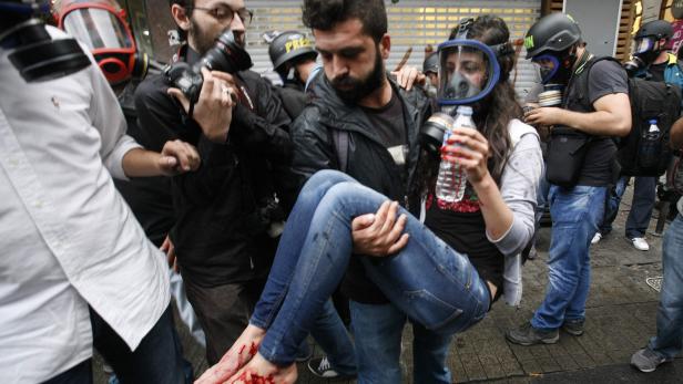 Ein Mann trägt eine verletzte Frau mit blutigen Füßen in seinen Armen.