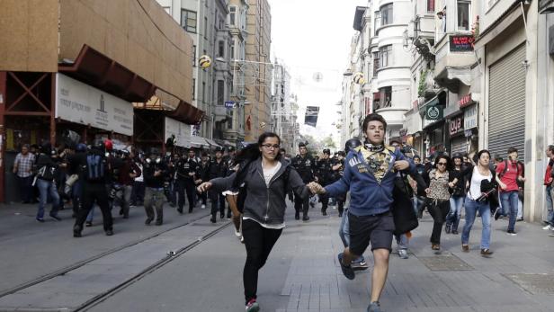 Menschen rennen in einer Straße in Istanbul vor einer Gruppe von Polizisten davon.