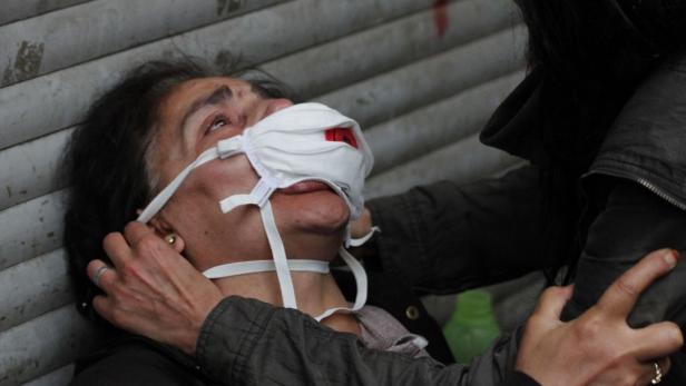 Eine Frau mit einer Gesichtsmaske wird von einer anderen Person gestützt.