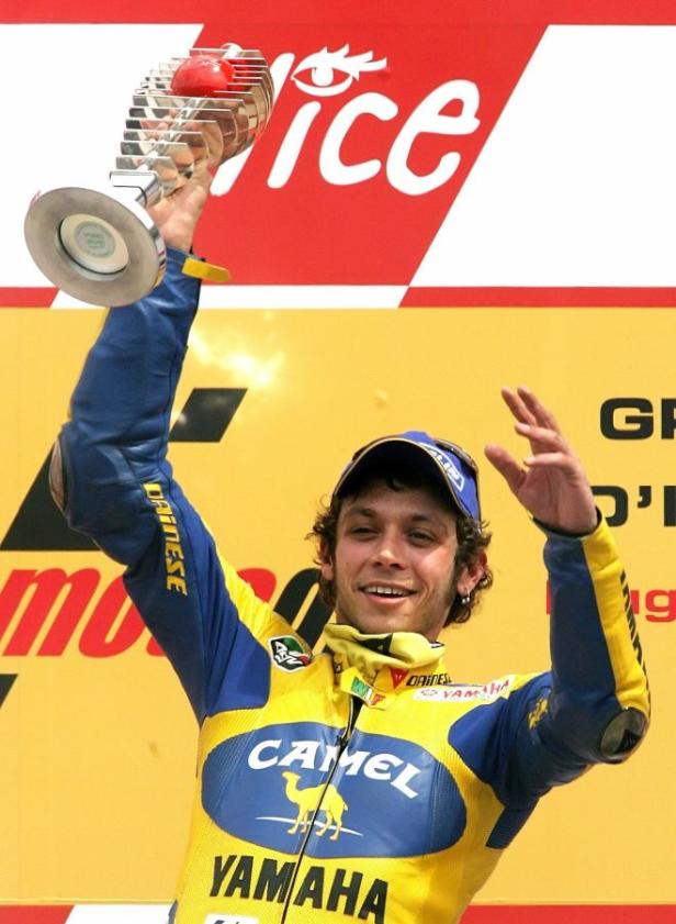 Valentino Rossi feiert mit der Trophäe auf dem Podium.