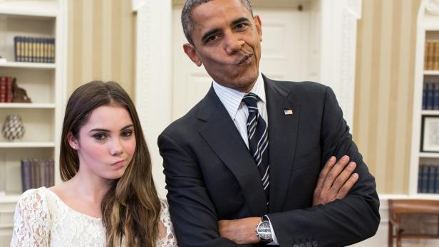 Barack Obama und eine junge Frau ziehen Grimassen vor einem Bücherregal.