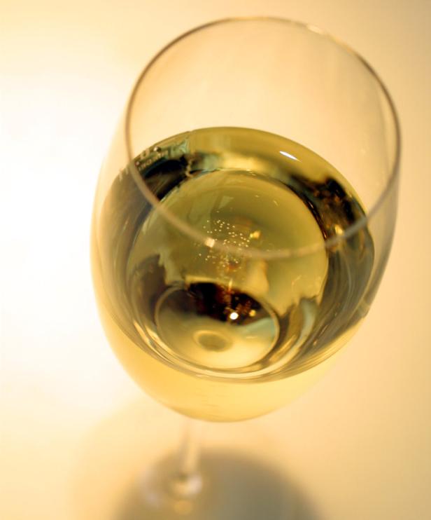 Ein Glas Weißwein steht auf einem hellen Untergrund.