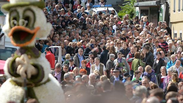 Eine große Menschenmenge beobachtet eine Parade mit einer Dagobert Duck-Figur.