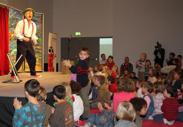 Ein Clown tritt vor einer Gruppe von Kindern auf einer Bühne auf.