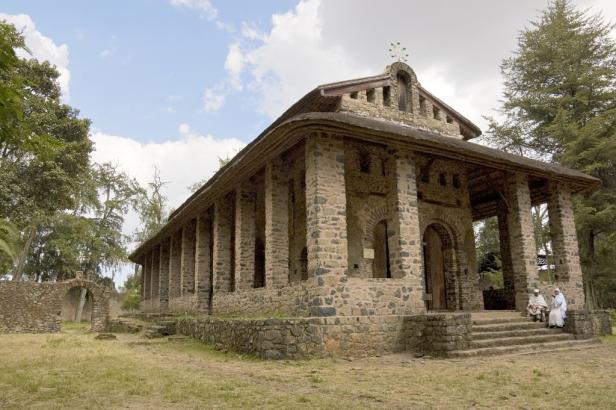 Die Kirche Debre Berhan Selassie in Gondar, Äthiopien, mit zwei Personen auf den Stufen.