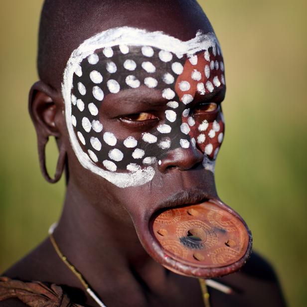 Ein Mann des Mursi-Stammes mit Gesichtsbemalung und Lippenteller in Äthiopien.
