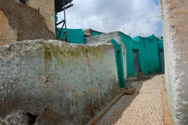 Eine Gasse mit türkisfarbenen Häusern und verputzten Mauern in Harar, Äthiopien.