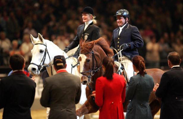 Zwei Reiter auf Pferden nehmen an einem Dressurwettbewerb teil.