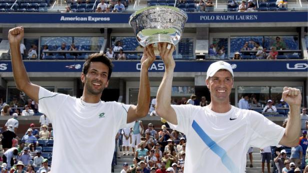 Zwei Tennisspieler halten gemeinsam die Trophäe der US Open in die Höhe.