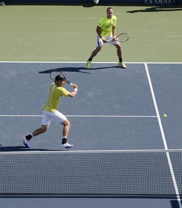 Zwei Tennisspieler auf einem blauen Hartplatz während eines Matches.