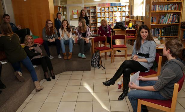 Eine Gruppe von Menschen sitzt in einer Bibliothek und unterhält sich.
