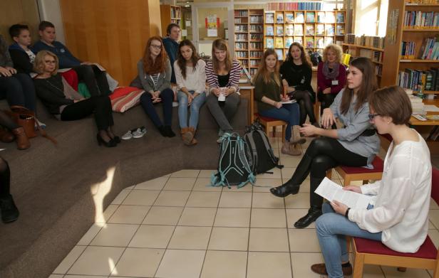 Eine Gruppe von Studenten sitzt in einer Bibliothek und diskutiert.