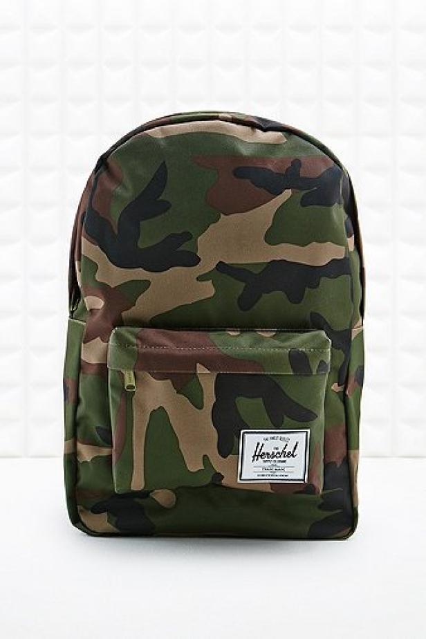 Ein Herschel-Rucksack mit Tarnmuster steht vor einem weißen Hintergrund.