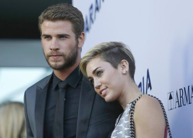 Liam Hemsworth und Miley Cyrus posieren zusammen auf einem roten Teppich.