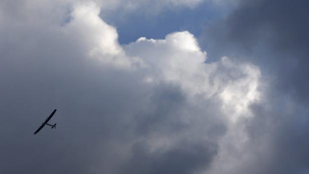Ein Flugzeug fliegt vor einem bewölkten Himmel.